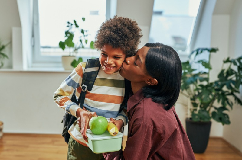 Mom kissing young child going to school