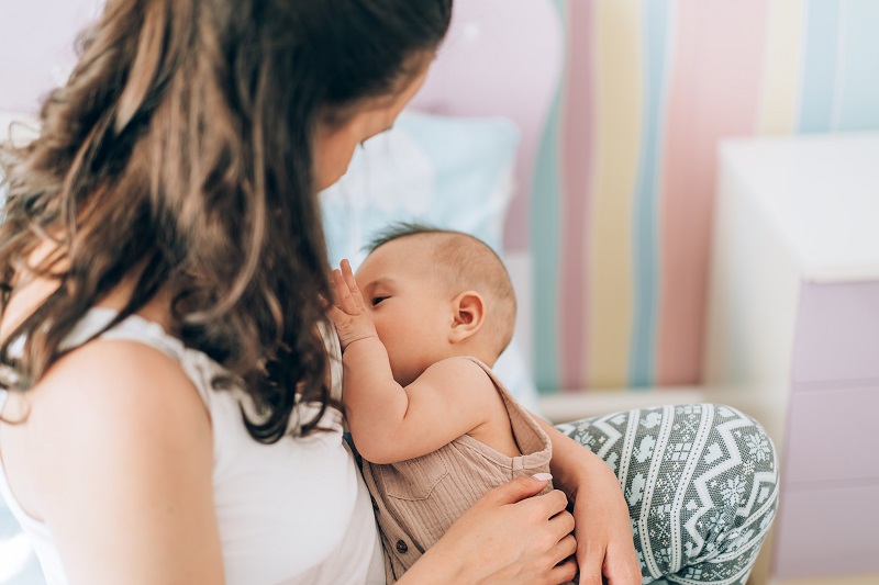 Mother breastfeeding her baby at home on the couch