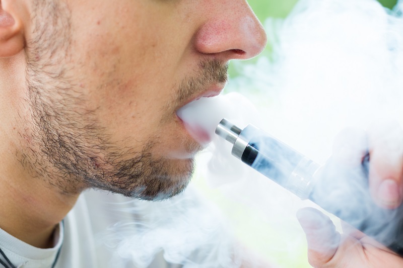 Close up of a man vaping an e-cigarette.
