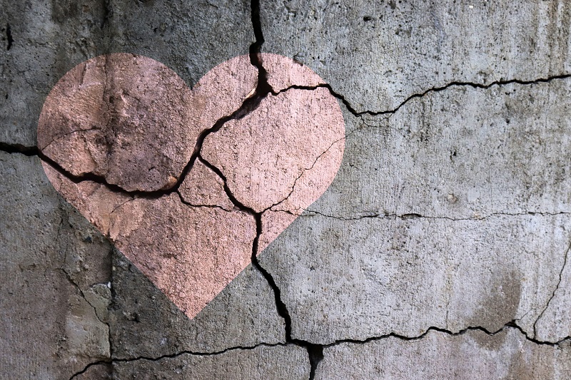 A broken heart; a drawing of a heart on a cracked wall. 