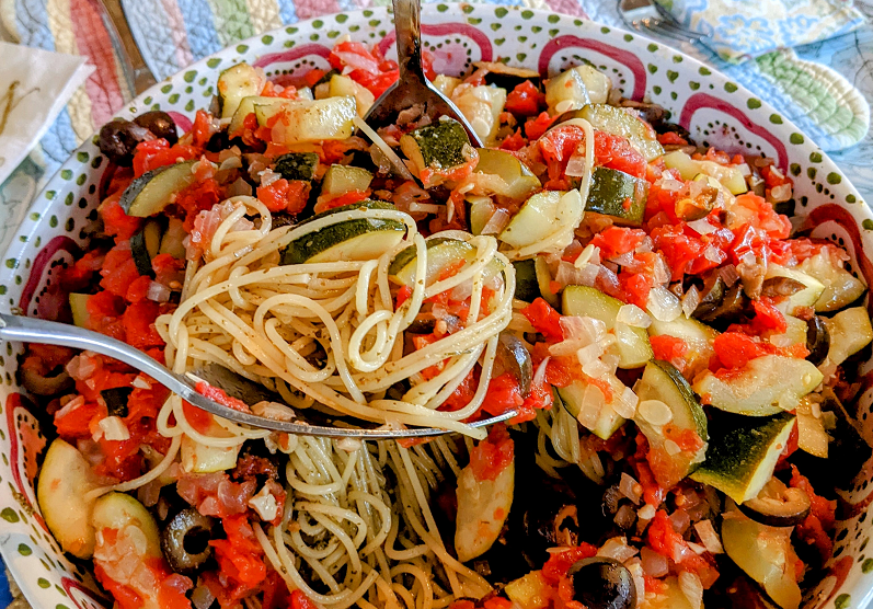 a pasta dish with garden vegetables and pesto