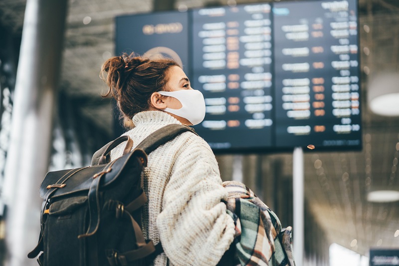 Young woman wearing a mask while traveling during the holiday season.