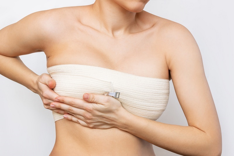 woman holding her bandaged breast after breast surgery