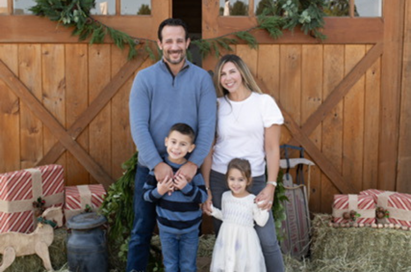 Lisa Silber poses in front of a barn door with her partner and two young children.