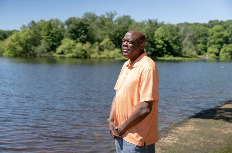 Standing near a scenic body of water, heart transplant recipient Joe Johnson gazes into the distance.