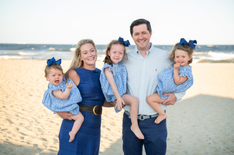 Allison Adams stands on a beach with her husband and three young daughters.