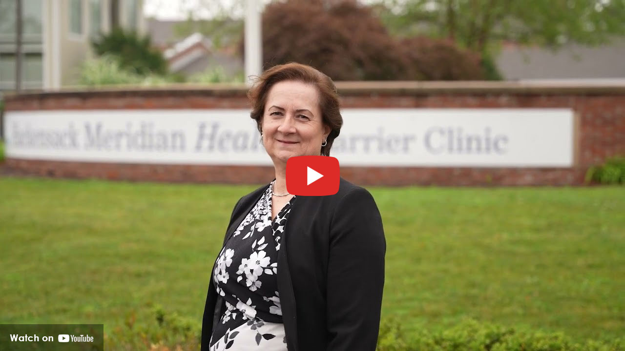 Woman standing outdoors in front of a Hackensack Meridian Health Carrier Clinic sign